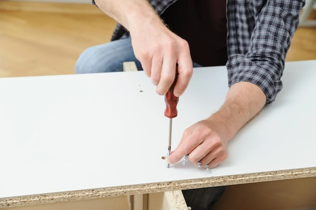 Mężczyzna instaluje śruby w płycie meblowej