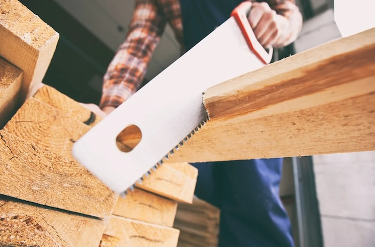 Stolarz przecina drewnianą deskę piłą