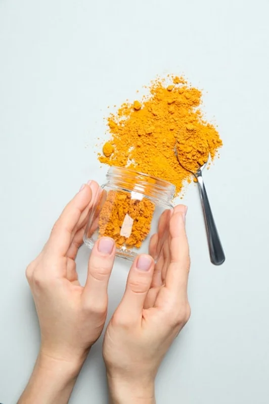 Proszek kurkumy w słoiku na jasnym tle