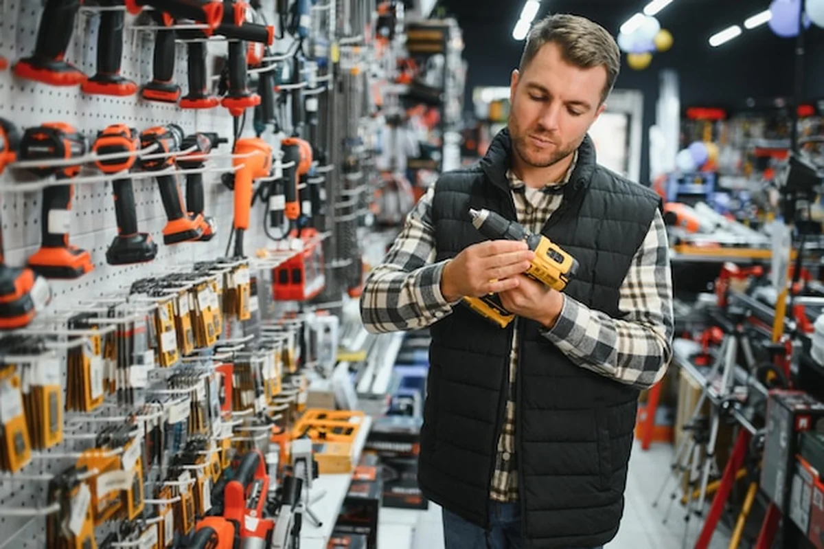 Mężczyzna wybiera narzędzie elektryczne w sklepie z narzędziami