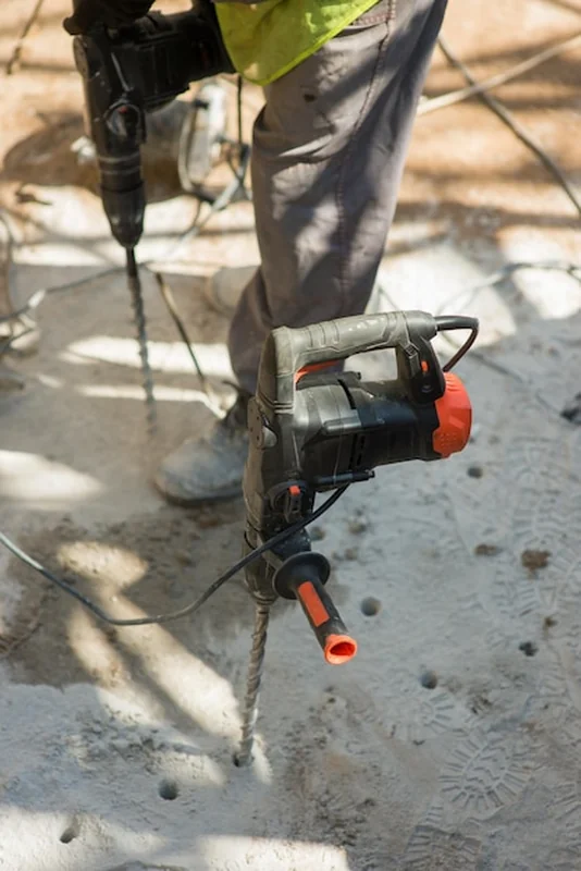 Budowniczy wierci otwory w betonowej płycie