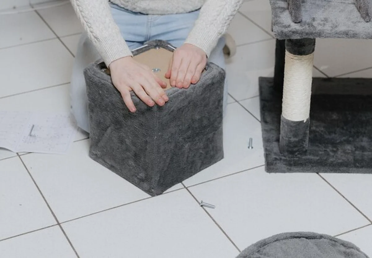 Młody człowiek montuje domek dla kotów w salonie