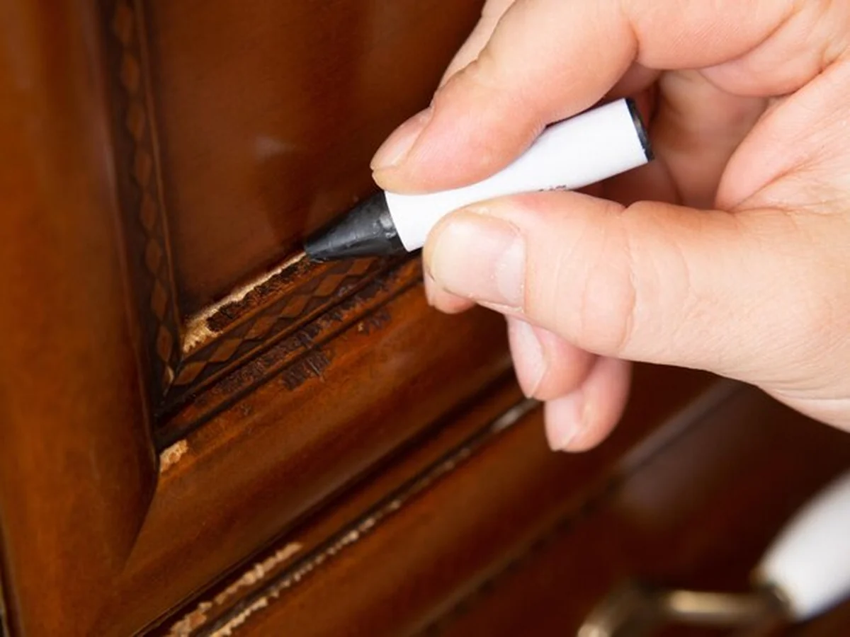 Mistrz naprawia zadrapanie na drewnianym meblu