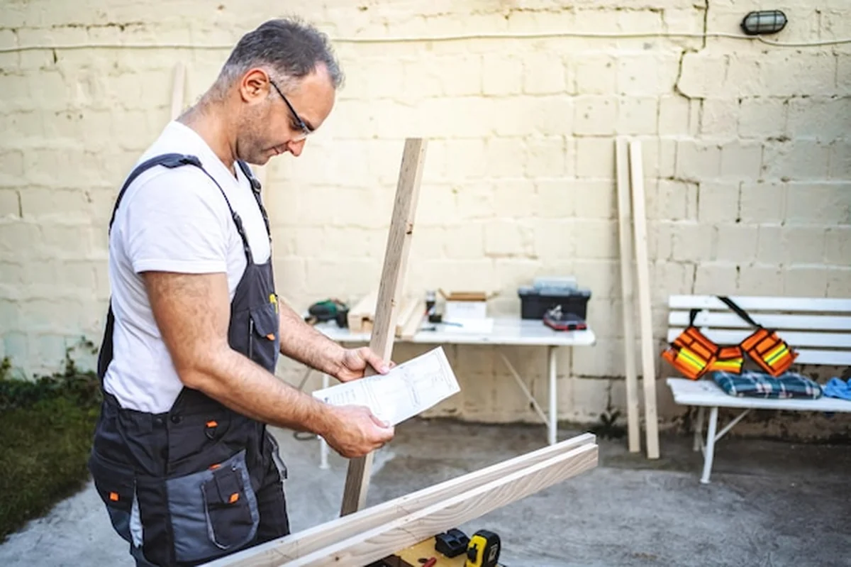 Dojrzały stolarz pracujący z drewnianą deską na świeżym powietrzu