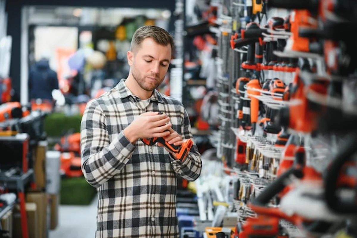 Mężczyzna wybiera narzędzie elektryczne w sklepie z narzędziami