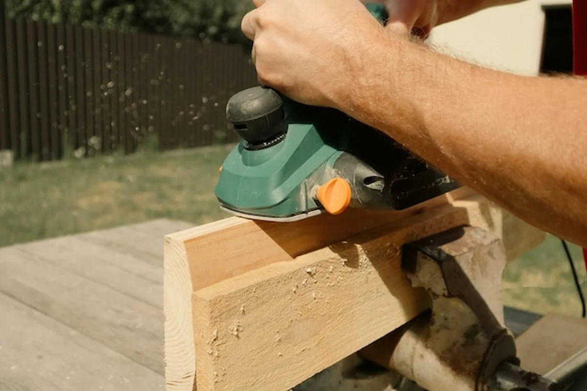 Stolarz rzuca drewniany kawałek drewna elektrycznym samolotem. Stolarz zrywa drewnianą deskę