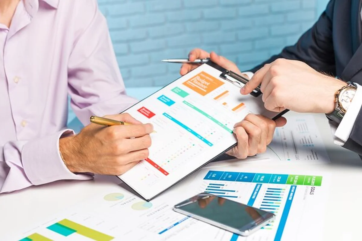 Profesjonaliści omawiają raporty finansowe przy stole z wykresami i grafikami