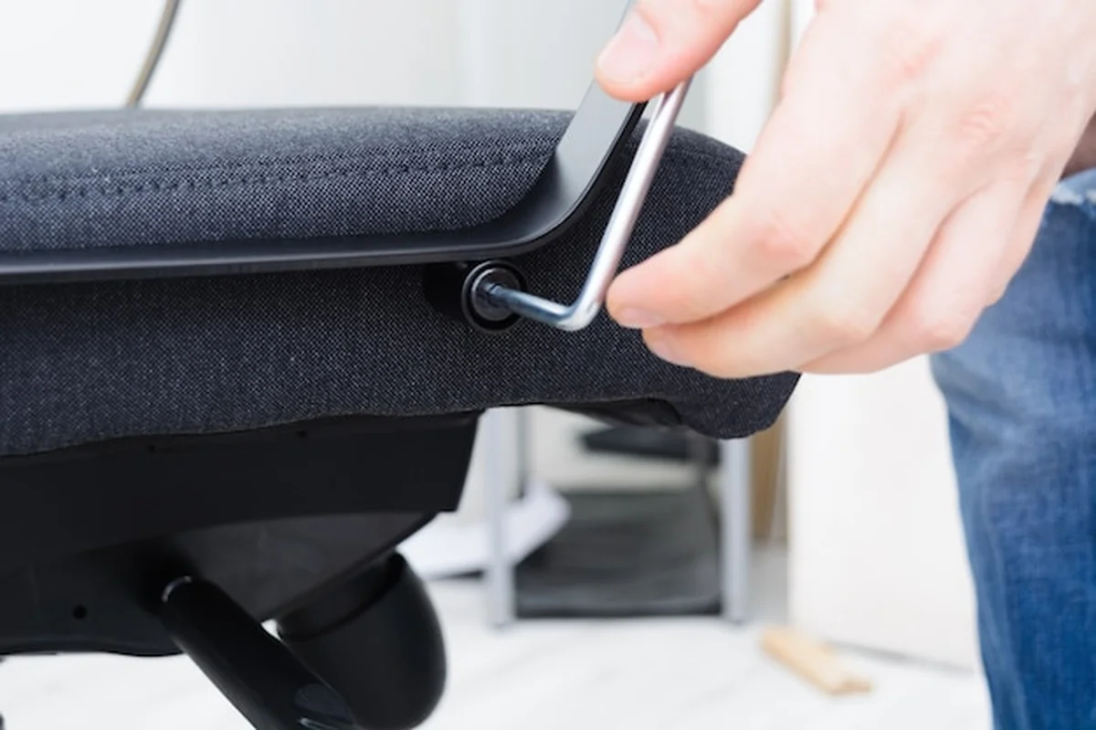 Ręce człowieka demontujące uchwyt krzesła obrotowego