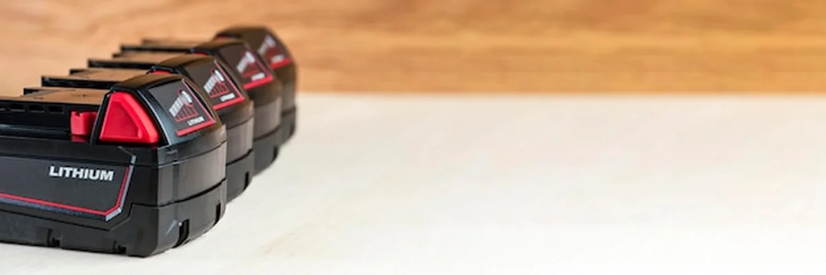 Cztery baterie do wkrętarki na drewnianym tle z ładowarką