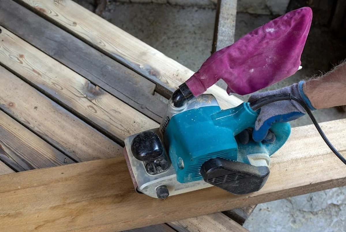 Mężczyzna szlifuje deski szlifierką
