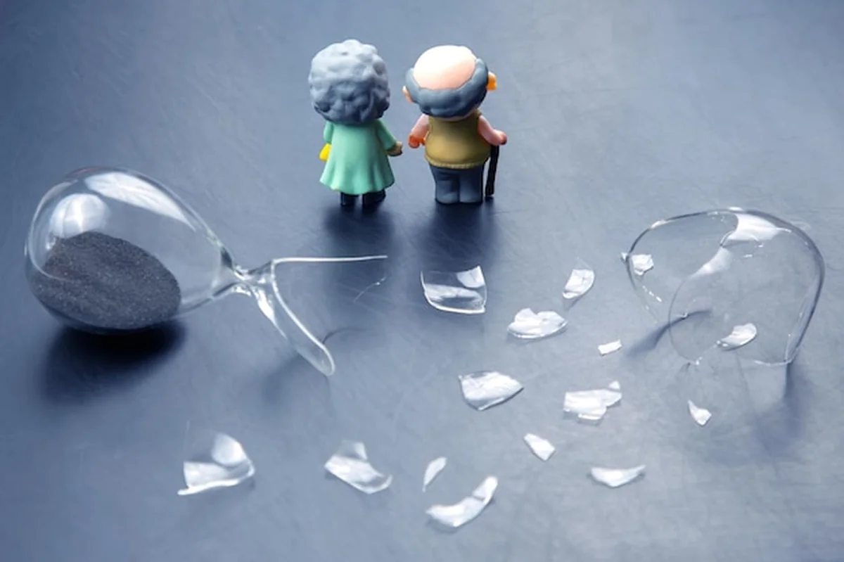 Para starszych ludzi przy rozbitej klepsydry