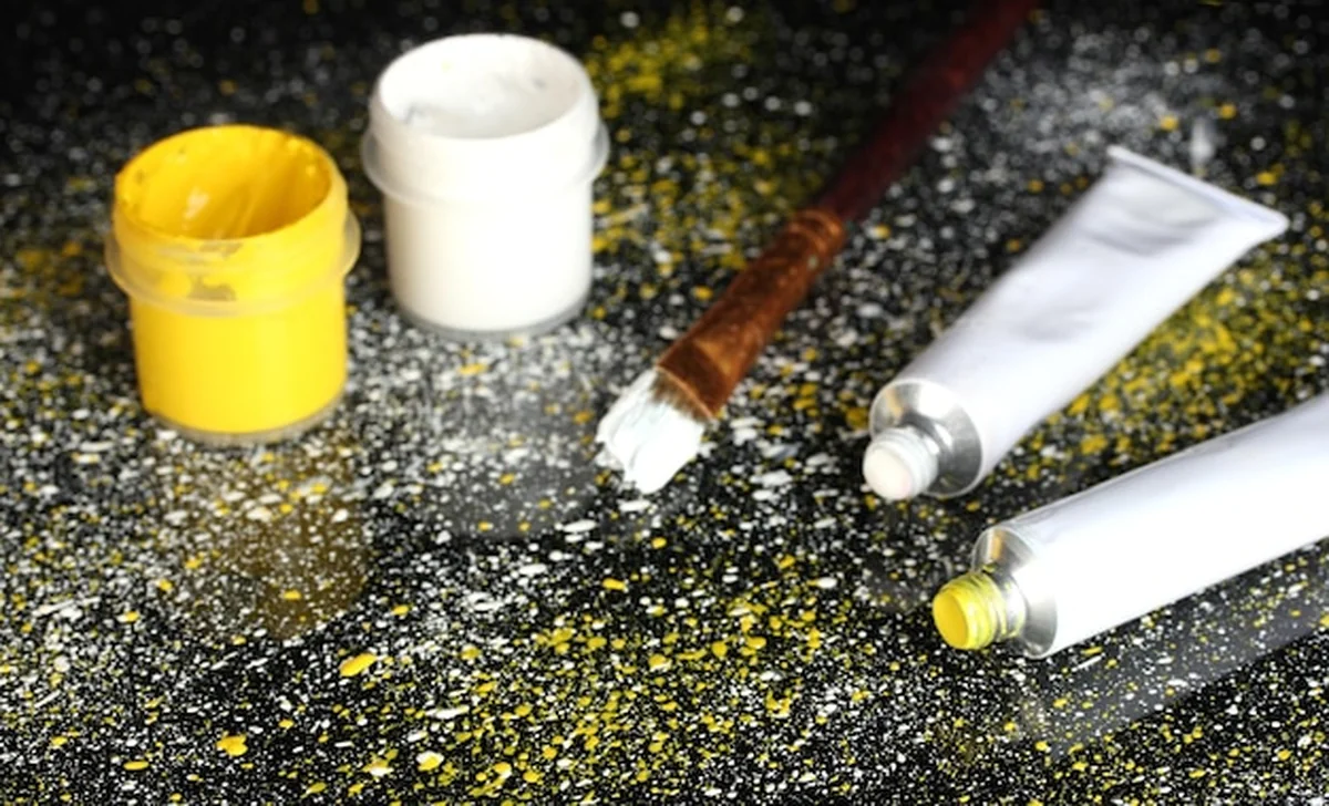 Słoiki z białym i żółtym pędzlem oraz rurki z białą i żółtą akwarelą na czarnym tle