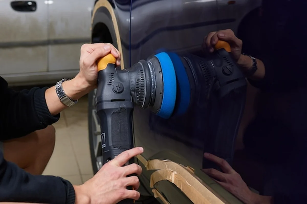 Mężczyzna poleruje samochód w warsztacie samochodowym