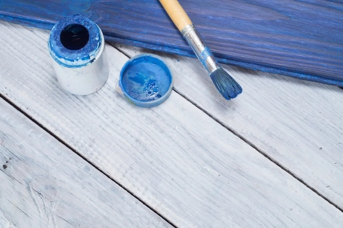 Niebieska farba i pędzel na tle białych tablic