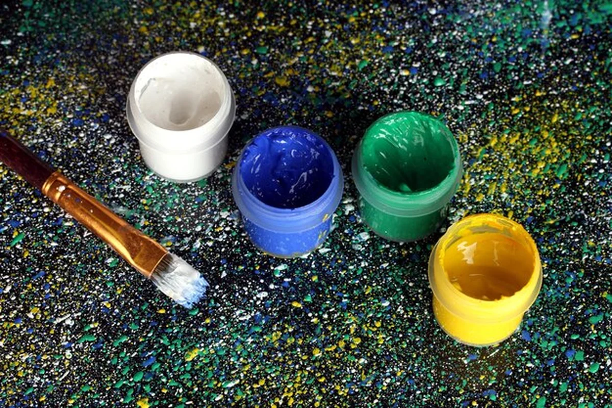 Słoiki z kolorowym gwaszem i pędzelkiem na czarnym tle