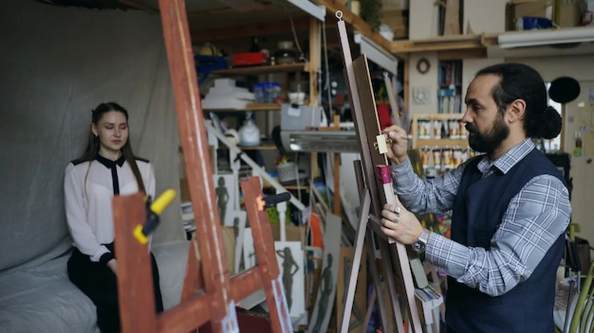 Rzeźbiarz tworzący rzeźbę na płótnie, młoda kobieta pozująca w pracowni artystycznej