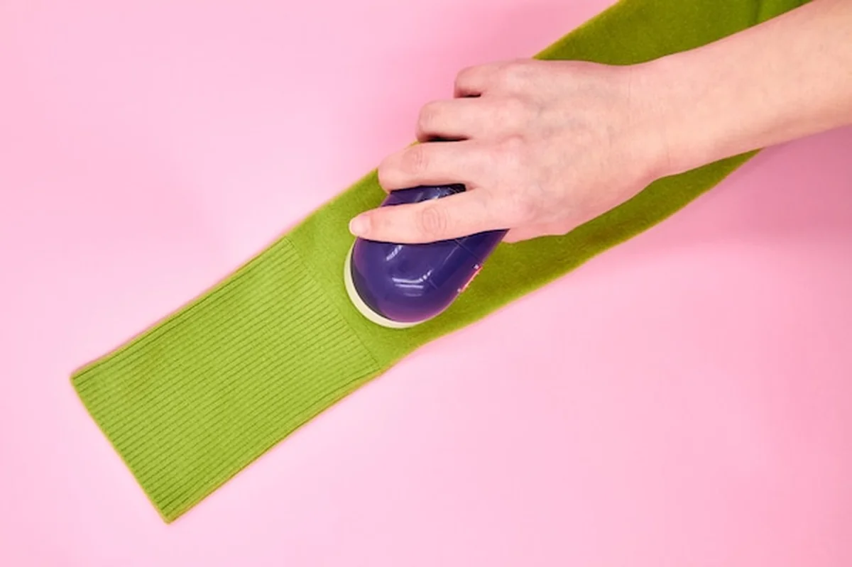 Kobieta usuwająca grudki tkaniny z odzieży przy użyciu golarki