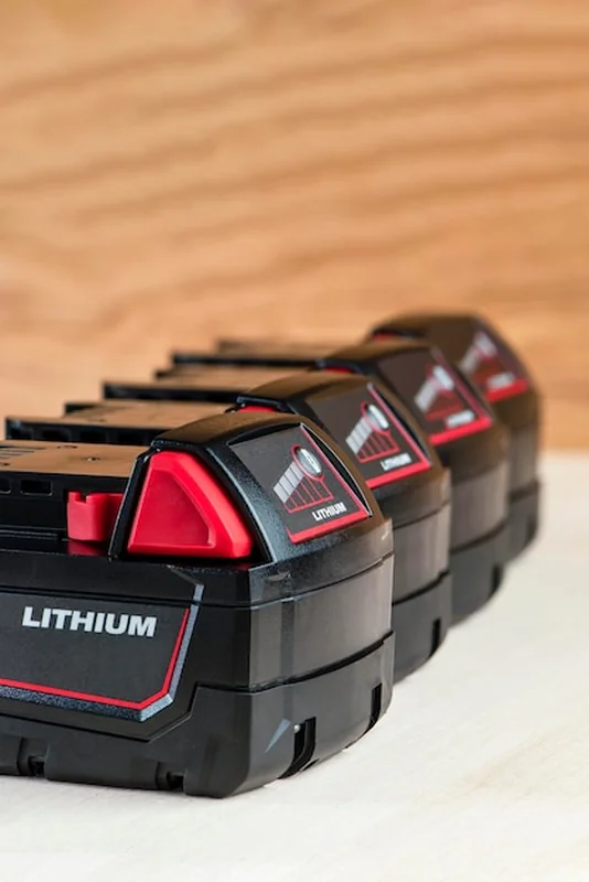 Cztery akumulatory do wkrętarki z wskaźnikiem naładowania na drewnianym podłożu