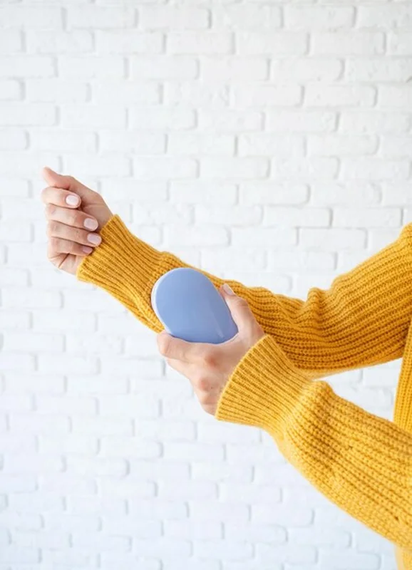 Kobieta usuwa granulki z ubrania na żółtym swetrze używając maszyny