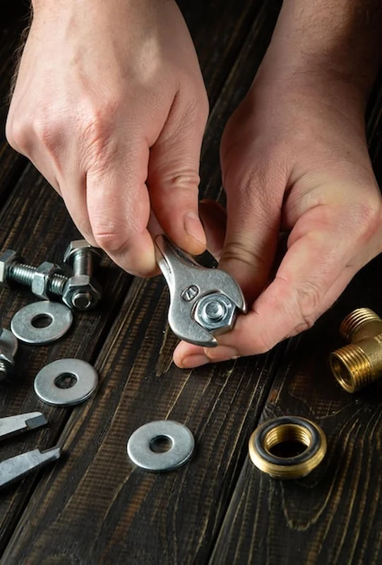 Mistrz dokręca nakrętkę kluczem na śrubie na stole warsztatowym