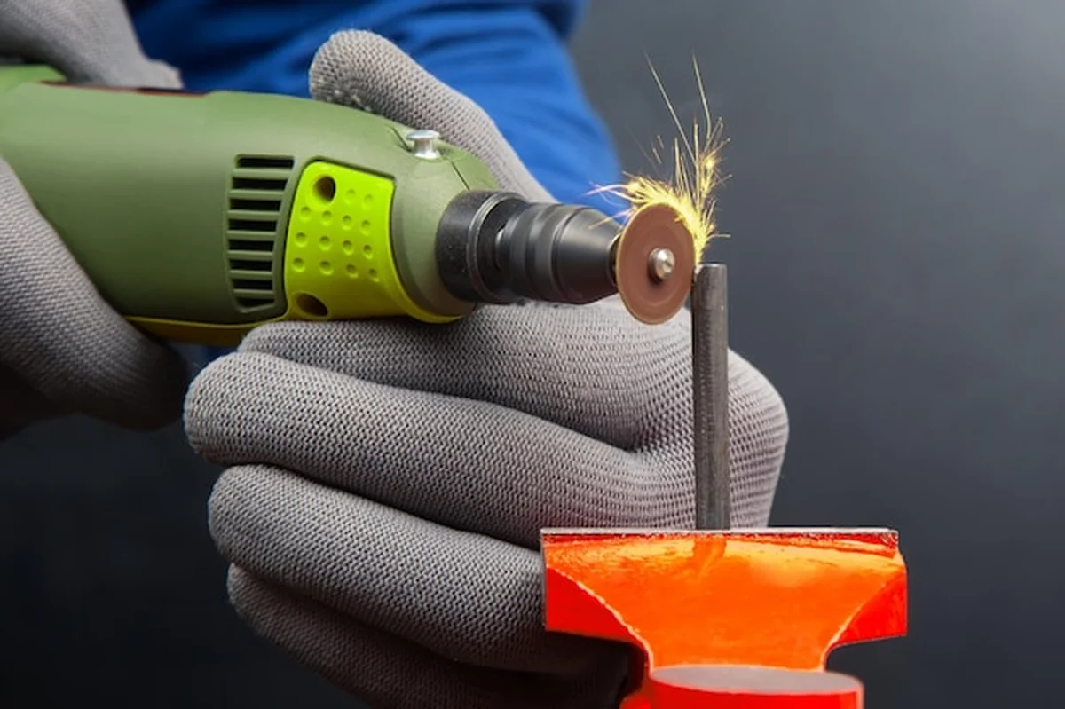 Pracownik graweruje metal wiertłem elektrycznym