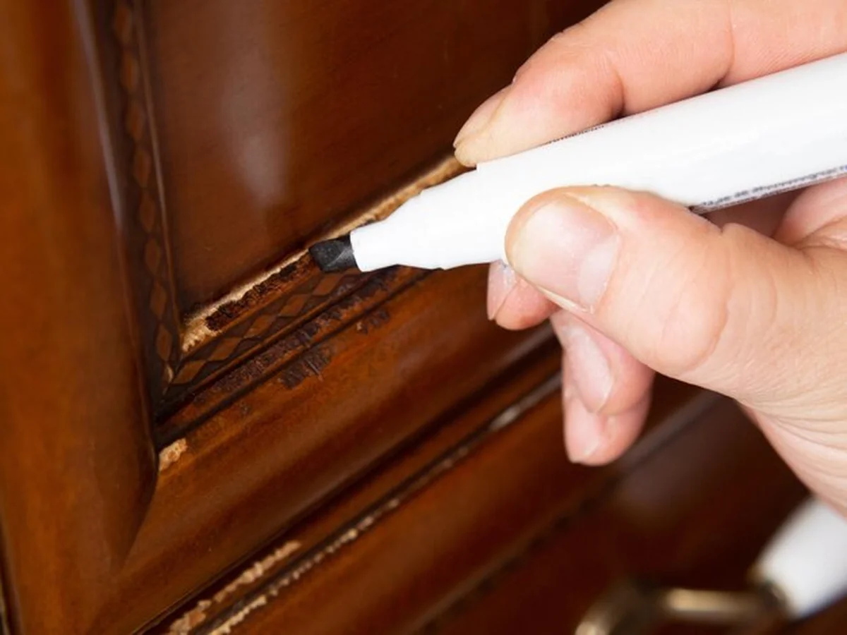 Mistrz naprawia zadrapanie na drewnianej fasadzie mebla