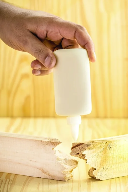 Stolarz nakłada klej do drewna na deskę