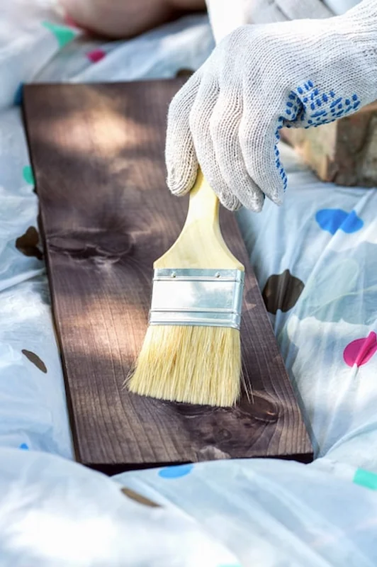 Ręka w rękawiczce maluje deskę pędzlem