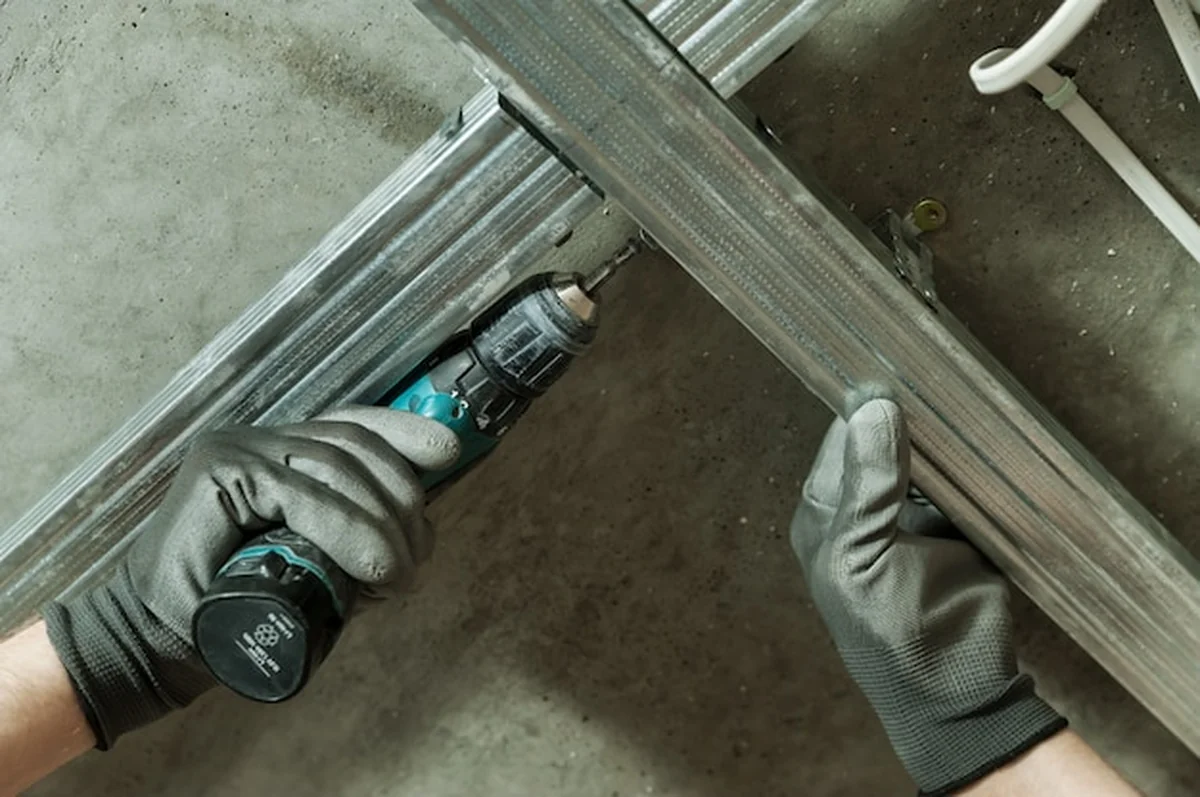 Mężczyzna montuje metalową ramę do sufitu gipsowo-kartonowego