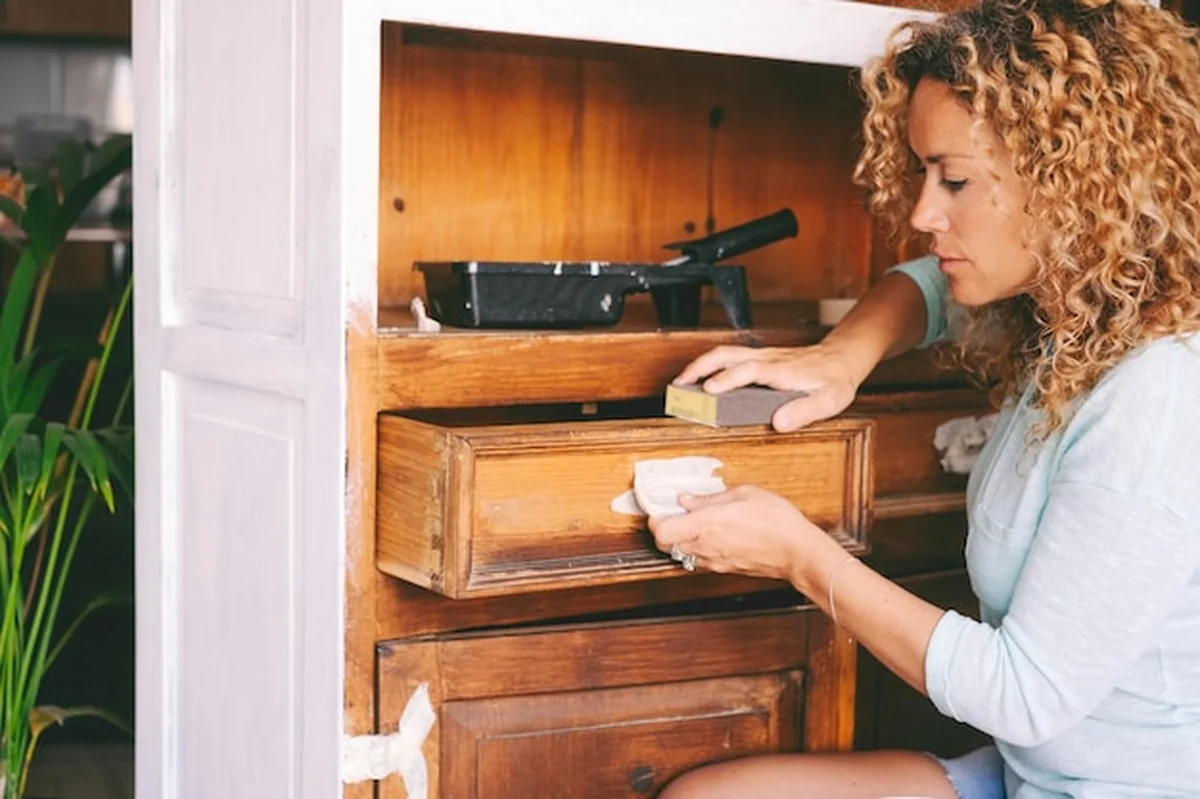 Kobieta odnawia drewnianą szafkę w domu