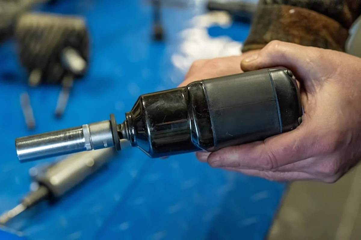 Mechanik trzymający klucz uderzeniowy w warsztacie samochodowym