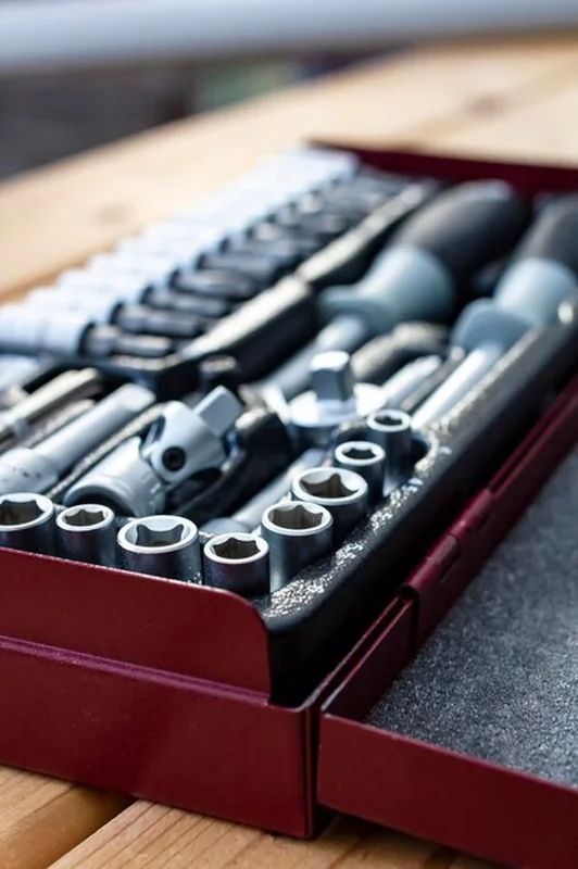 Metaliczne czerwone pudełko z kompletem kluczy na drewnianym stole