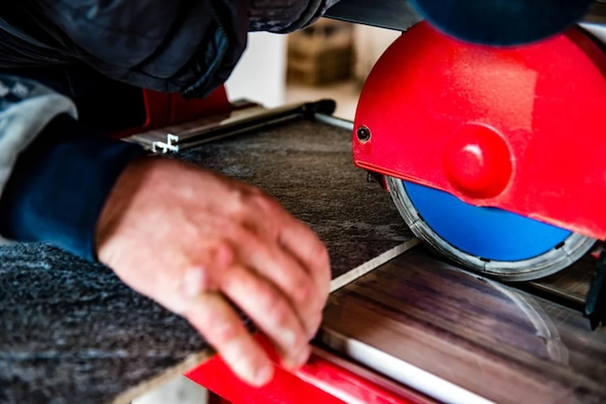 Pracownik tnie płytkę ceramiczną na przecinarce na mokro