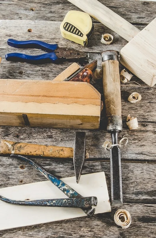 Narzędzia stolarskie na drewnianej ławce, struganie, dłuto, młoteczku, taśmie mierniczej, młotku, szczypcach, widok z góry