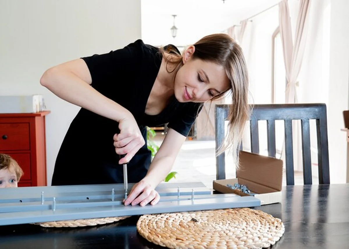 Kobieta z śrubokrętem instalująca meble w domu