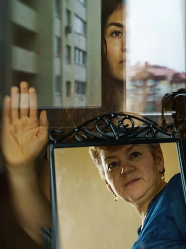 Kobieta odzwierciedlona w lustrze i kobieta patrząca przez okno